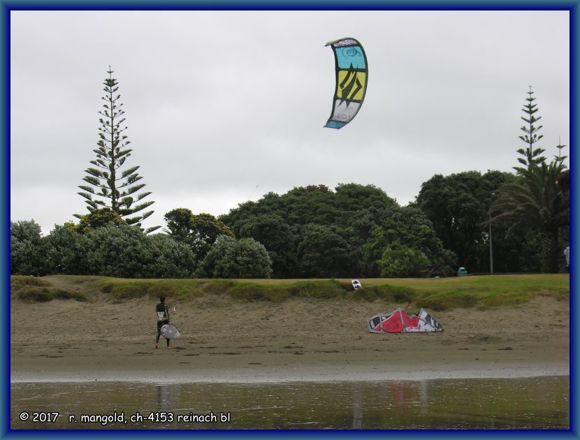 ein kitesurfer legt seinen zweiten schirm am 04.12.2011 bei orewa beach (neuseeland) am strand ab